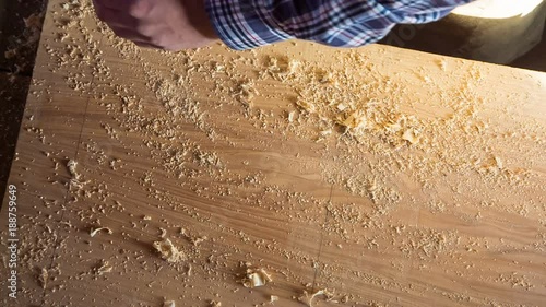 The carpenter sweeps the saw from the board and check its quality. Top view