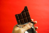 チョコレートを食べる　かじったチョコレートと手　赤色背景