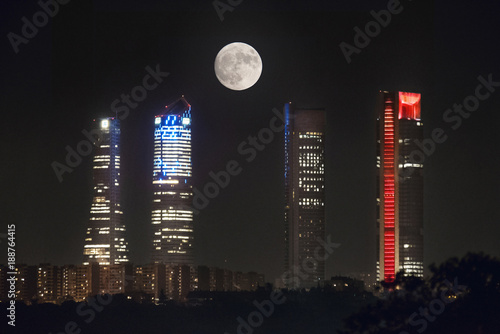 Full moon over Cuatro Torres business area skyline at night in Madrid, Spain.
