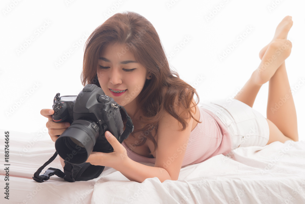 Portrait of beautiful asian woman holding and looking at her camera isolated on white background. Female photography holding camera.