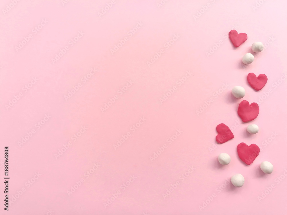Plasticine clay made are beautiful red heart and white balls, arrange line on right and placed on pink paper background