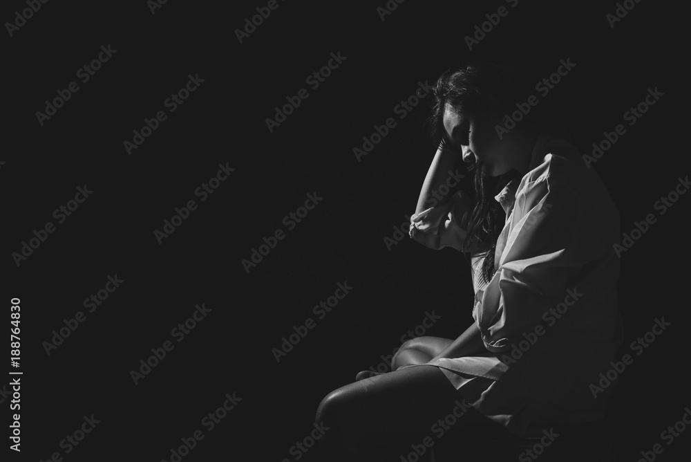 The depression woman sit on the chair on dark background, sad  asian woman silhouette in dark, monochrome image. Free from copy space.