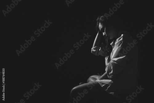 The depression woman sit on the chair on dark background, sad  asian woman silhouette in dark, monochrome image. Free from copy space.
