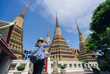 Young asian woman traveler with backpack and hat looking the map with Grand palace and Wat phra keaw at Bangkok Thailand