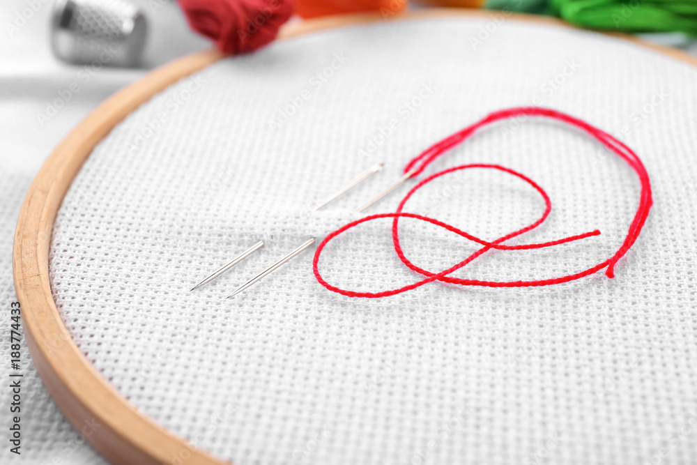 Embroidery hoop with fabric, sewing needles and thread, closeup Embroidery hoop with fabric, sewing needles and thread, closeup