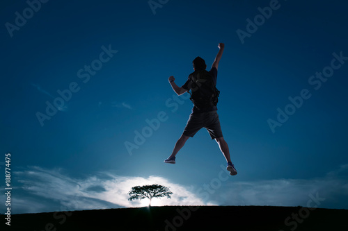 Silhouette image of young guy cheer and jump up with cold tone sunset landscape . success, leadership and achievement concept .