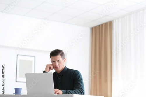 Young man using laptop at t...