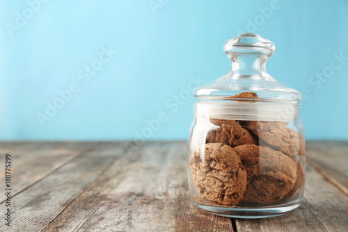 Fotografering Delicious oatmeal cookies with chocolate chips in glass jar on wooden table