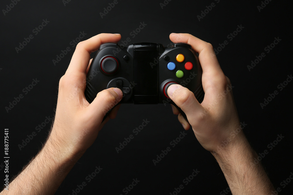 Fototapeta premium Man holding video game controller on black background