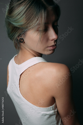 Girl in a white tank top on a gray background. Side view