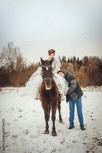 Bride and groom walking with horse in a winter afternoon