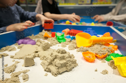 Kids playing plastic mold toys with sand on sandbox. Background blurry.