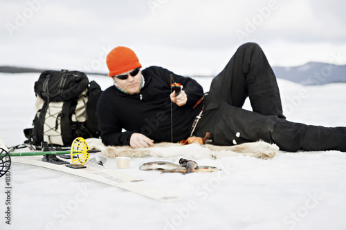 Man lying on snow and fishing photo