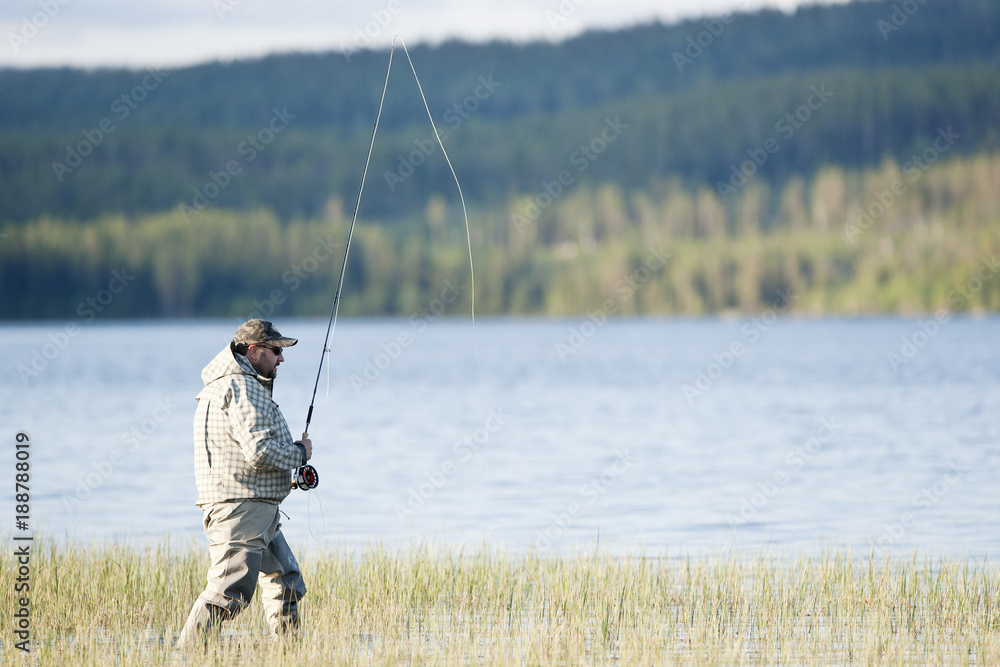 Man standing in reed with fishing rod Man standing in reed with fishing rod