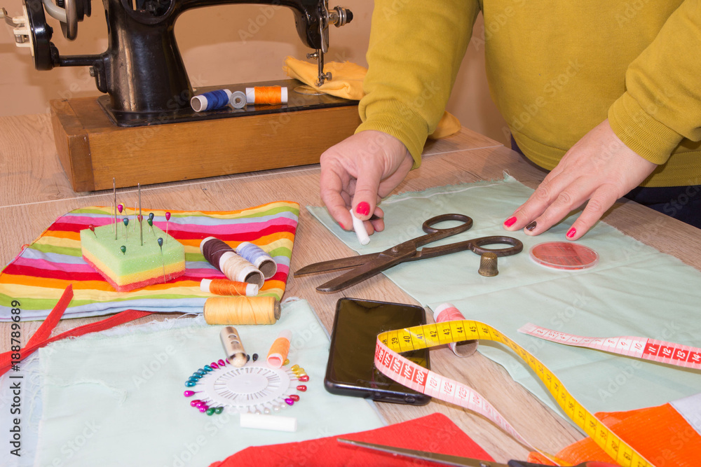 Seamstress hands on the work table with measuring tape. Tailor hands working with scissor and suit textile cloth Seamstress hands on the work table with measuring tape. Tailor hands working with scissor and suit textile cloth
