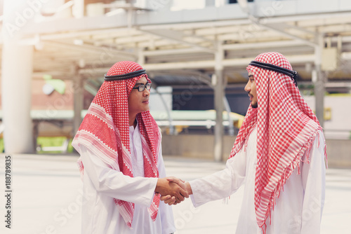 Two  Arabian businessman smile and shaking hands after meeting and over deal their agreement to sign agreement or contract. photo