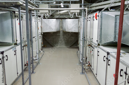 Two gray industrial air handling units in the ventilation plant room with big size ductworks and pipelines photo