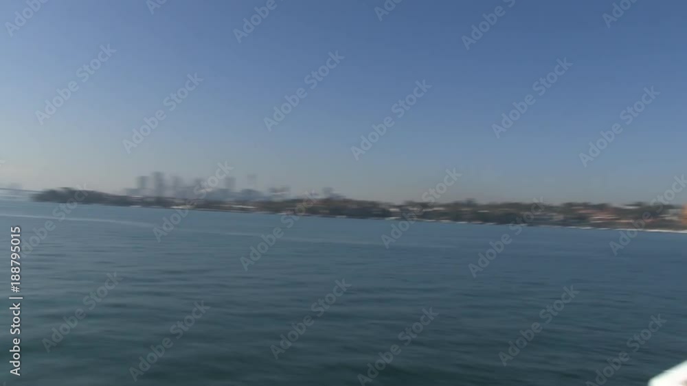 A wide shot of the ocean with buildings and cities from afar. Camera pans to the right to show the bow's boat A wide shot of the ocean with buildings and cities from afar. Camera pans to the right to show the bow's boat