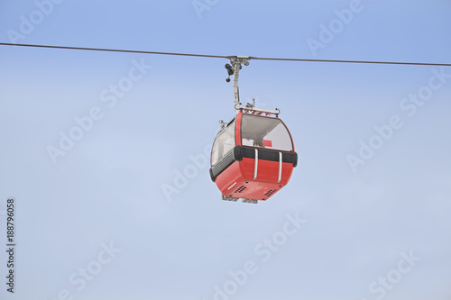 Red gondola car lift on the ski resort against blue sky