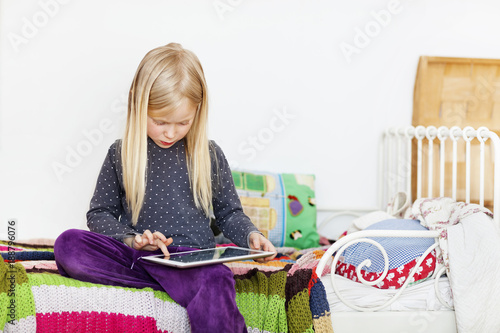Girl sitting on bed using tablet