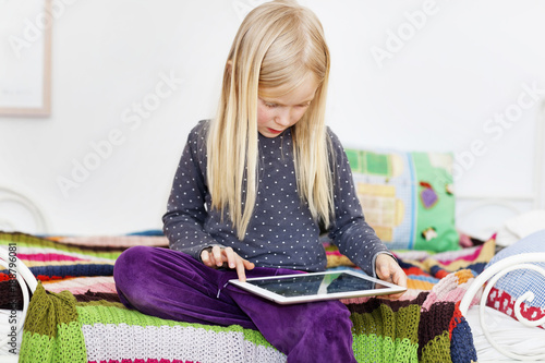 Girl sitting on bed using tablet