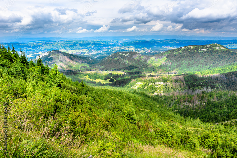 Fototapeta premium Green valley and hills in mountains with city panorama, mountain landscape