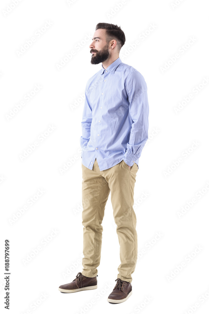 Side view of elegant handsome bearded business man looking up smiling with hands in pockets. Full body length portrait isolated on white background. Side view of elegant handsome bearded business man looking up smiling with hands in pockets. Full body length portrait isolated on white background.