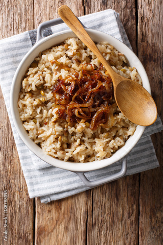 Stewed rice with lentils and fried onions close-up in a bowl. Vertical top view