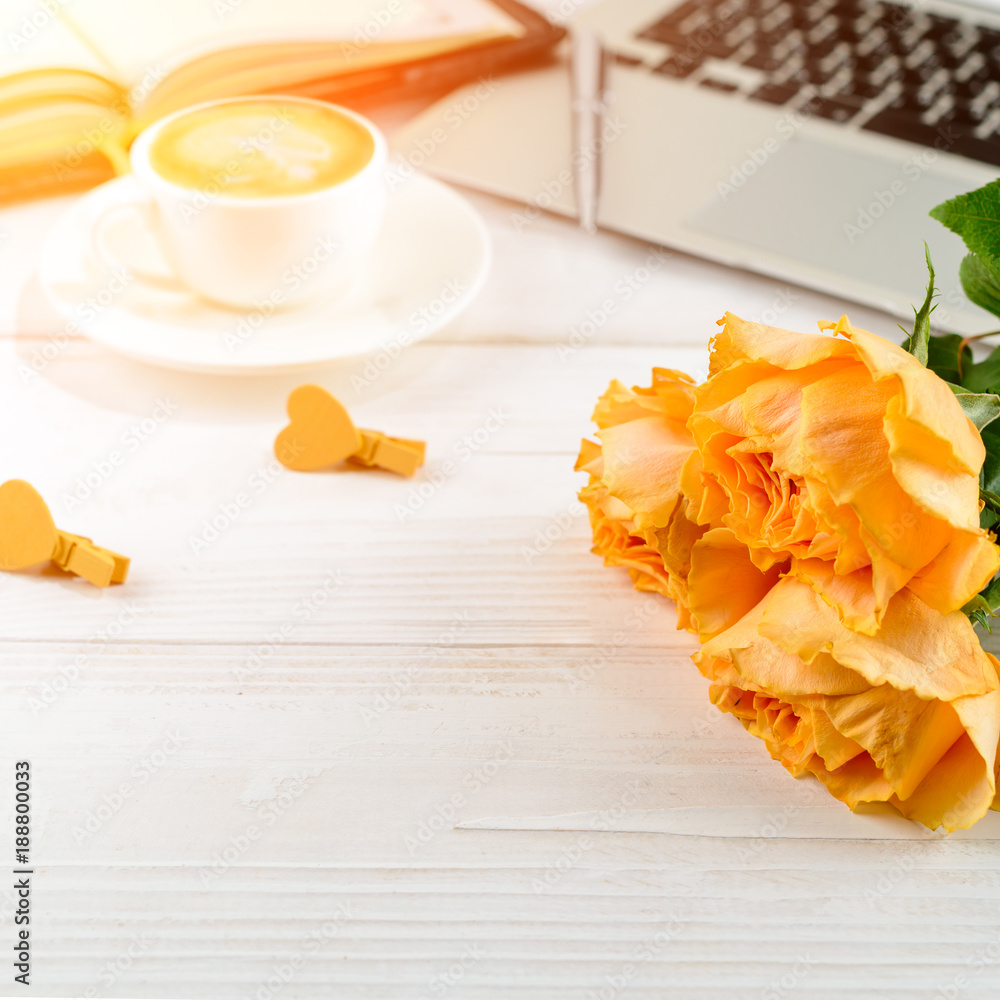 Have A Nice Day concept. Cup of coffee with fresh beautiful flowers and laptop on light table in rays of the sun