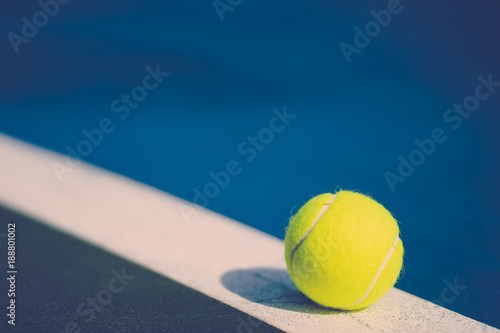Foto one new tennis ball on white diagonal line in blue hard court with light from ri