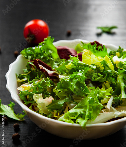 various fresh mix salad leaves with lettuce, radicchio, and rocket in bowl on dark wooden background