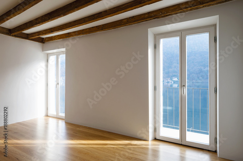 Empty room with large windows and antique beams