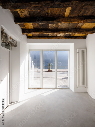 Empty room with large windows and antique beams