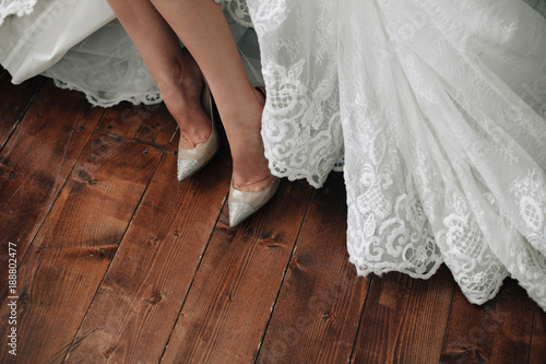 bride in a dress and shoes is standing on wooden floor © tatyanasuyarova