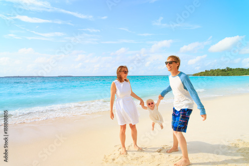 family with little baby playing on tropical beach