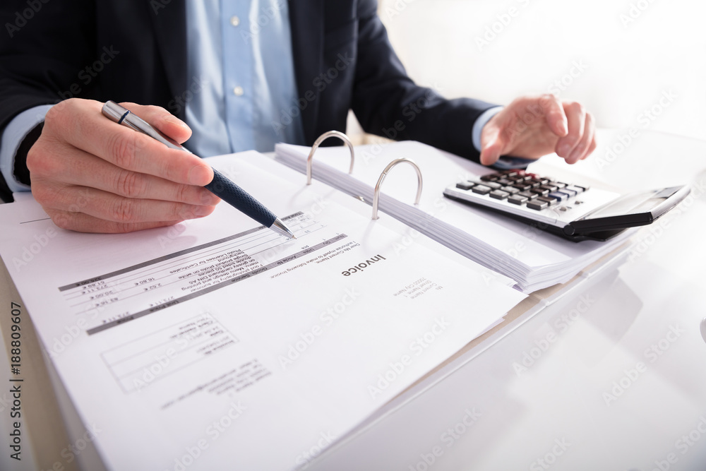 Businessperson Checking Invoice With Calculator Businessperson Checking Invoice With Calculator