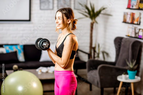 Young woman doing sports with dumbbells at home