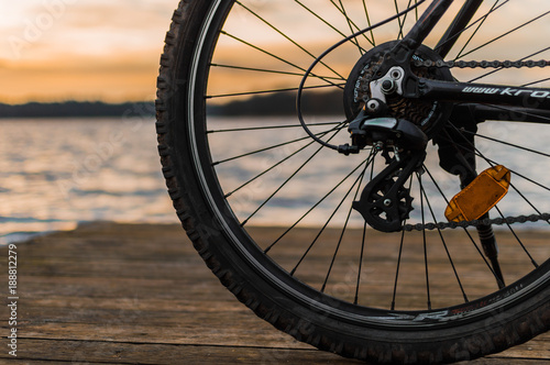 Mountain bike standing on a wooden bridge with lake and sunset in the background - selective focus