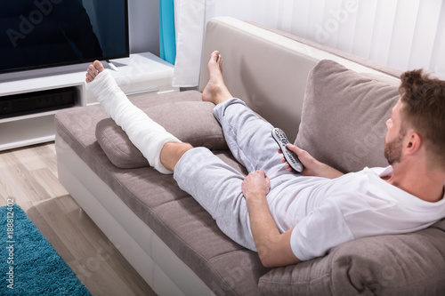 Man With Broken Leg Holding Remote Near Television
