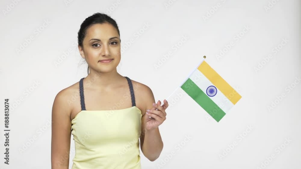 Young female standing smiling at camera holding national flag of India, over white background Young female standing smiling at camera holding national flag of India, over white background