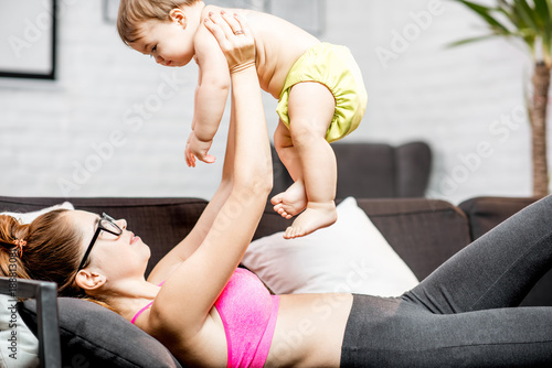 Sports mom holding her baby boy lying on the couch at home