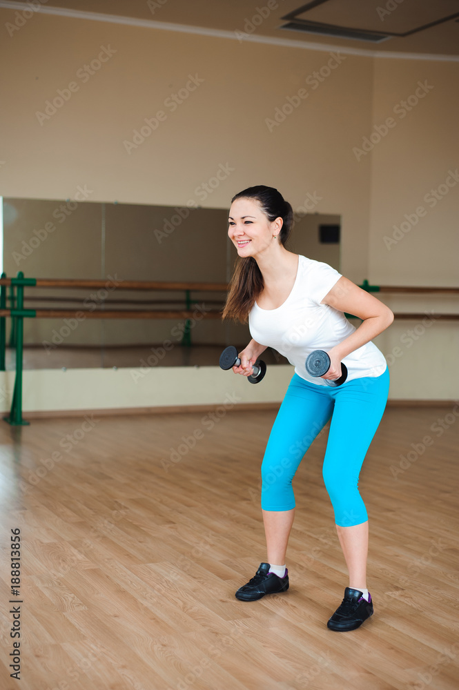 athletic young woman doing exercises with dumbbells in the gym athletic young woman doing exercises with dumbbells in the gym