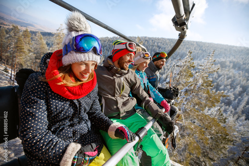 Happy people in ski lift lifting on ski terrain