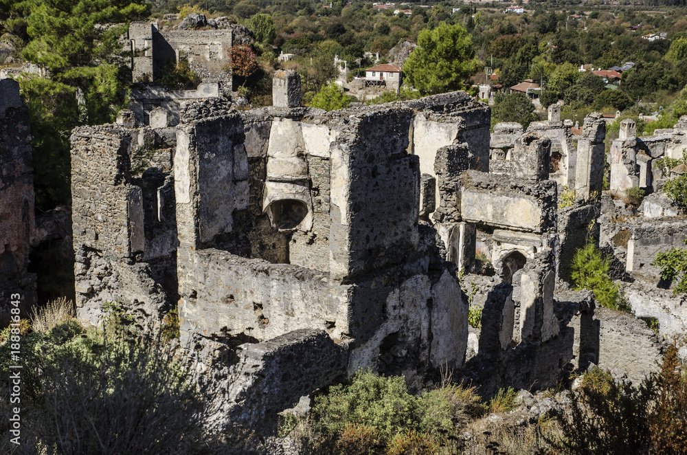 Turkey, the ghost town of Kayakoy, on the slope of the mountain abandoned houses, close-up depicts the walls of the destroyed houses, in the foreground the destroyed Greek hearth