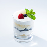 Delicious sweet dessert with berries and mint in a glass on light background