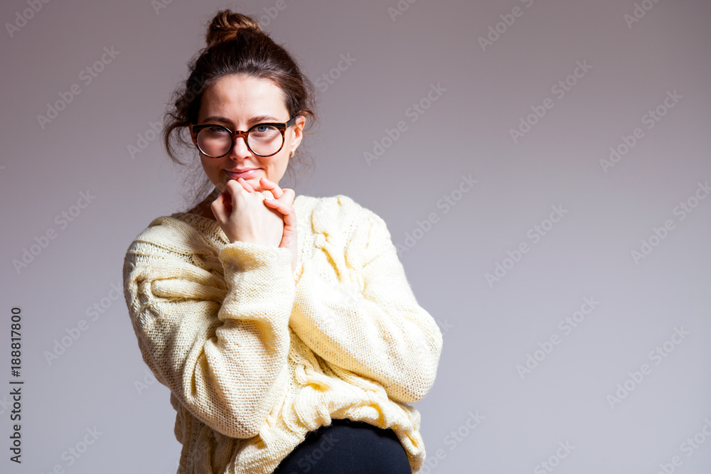 Portrait of a young dark-haired beautiful woman in her late pregnancy with glasses and a knitted milk-colored sweater on a white isolated background
