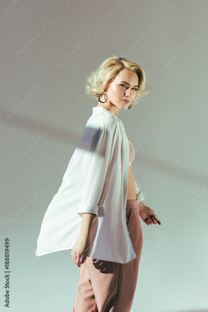 beautiful blonde woman in pink bra, shirt and pants looking at camera on grey beautiful blonde woman in pink bra, shirt and pants looking at camera on grey