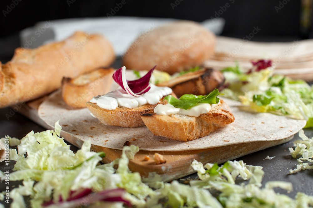 sandwiches with fresh herbs, sour cream and cheese and bread on a dark background
