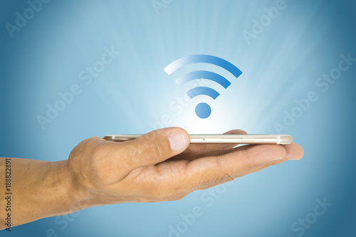 Hand holding smart phone with wifi logo and light on a blue background