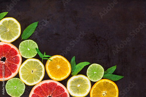 Fototapeta Naklejka Na Ścianę i Meble -  corner with slice of oranges, lemons, limes, grapefruit and mint pattern on black. Flat lay